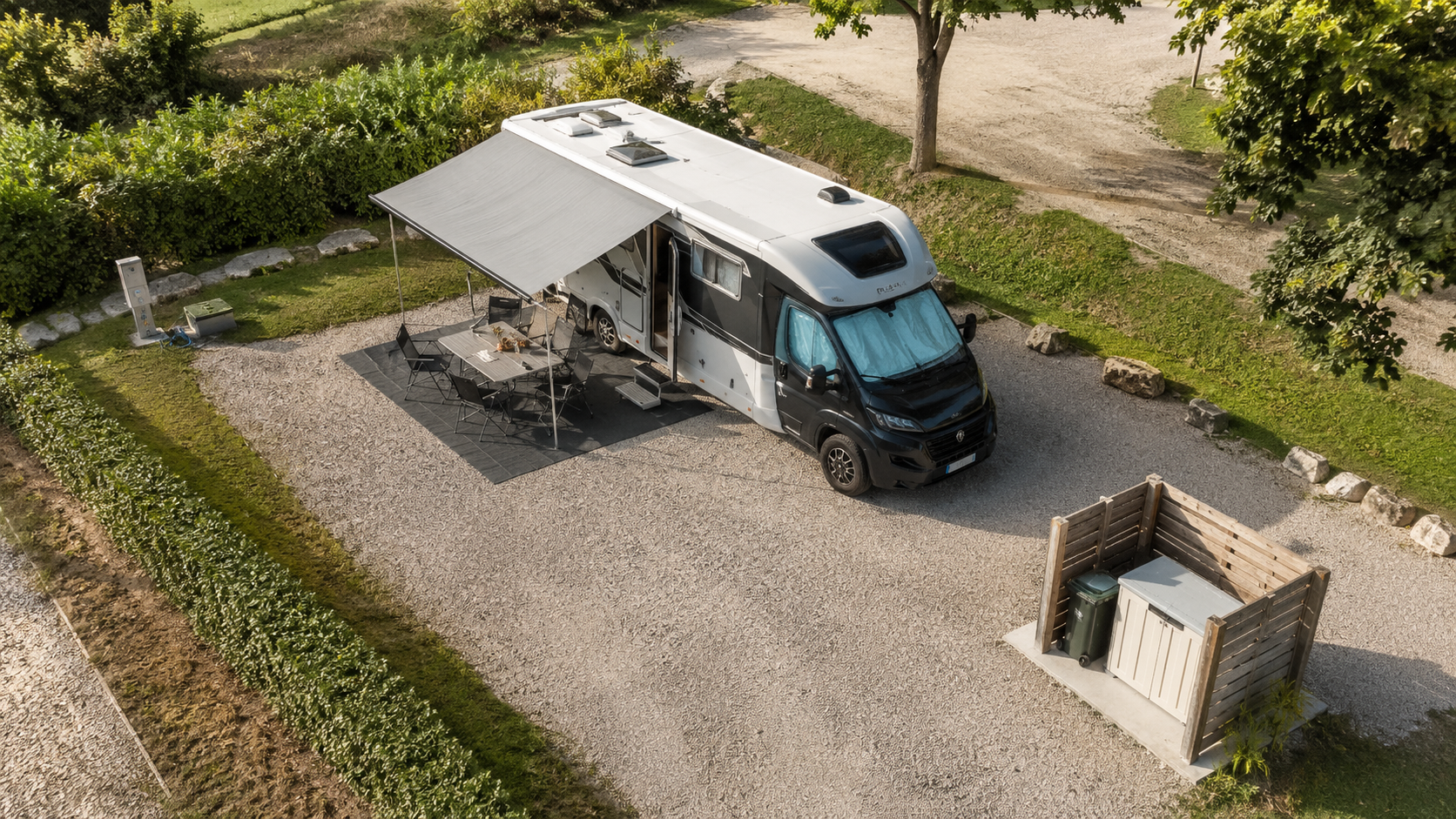 Vista dall alto di una piazzola camper con mezzo, area tavolo, allacci e spazio tecnico